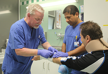 Arzt und Pfleger legen einen Verband an einem Arm an.